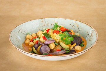 Mixed vegetable Thai curry with rice in a bowl with a light brown background