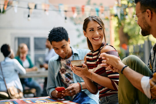 Happy woman enjoys in cup of coffee while talking to her friends in cafe.