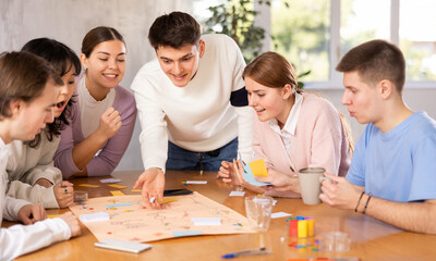 Group of positive younger people playing tabletop game