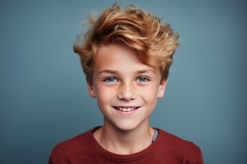 Portrait of a smiling little boy with blond hair on blue background