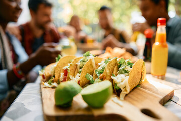 Close up of tacos with group of friends in background.
