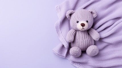 Fototapeta premium A small knitted amigurumi bear toy on a violet blanket, on a violet background. Flat lay, top view, copy space. space for text