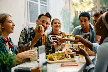 Young happy people having lunch together in Mexican restaurant.