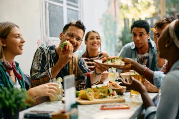 Fotobehang Young happy people having lunch together in Mexican restaurant. © Drazen