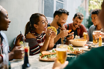 Young woman eating tacos while being with friends in Mexican restaurant.