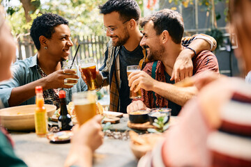 Happy male friends toasting while gathering in cafe.
