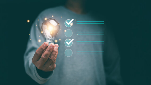 Concept of successful business and thinking solution strategy. Businessman holding glowing light bulb and have checklist for solving problem. Check and solution list to business target.