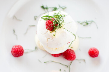 Close up top view of white chocolate cream and lavender meringue with raspberries on white plate in restaurant