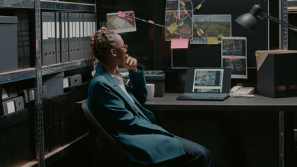 Private detective studying crime case information on board in archive room, examining files and forensic evidence. Law agent searching for suspect to solve felony, uncover details. Handheld shot.