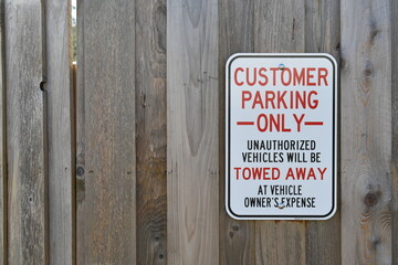 Tow away zone, threatening sign on wooden fence.