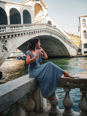 Young woman in long blue dress in front of the Rialto Bridge in Venice