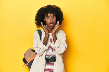 Teen girl with backpack, camera, ready for vacation surprised and shocked.