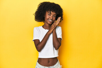 Teen girl in classic white T-shirt, yellow studio backdrop feeling energetic and comfortable,...