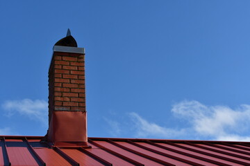 Red metal roofing with red brick chimney and flashing.