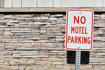 No motel parking sign. Stone veneer siding in the background.