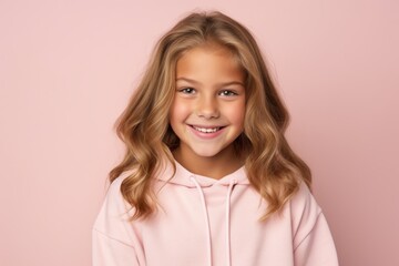 Portrait of a smiling little girl in a pink hoodie on a pink background