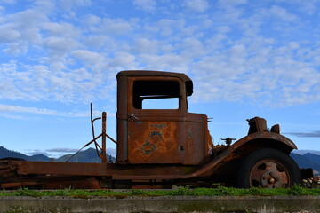 Classic rusted car chassis against clear blue sky. - Powered by Adobe
