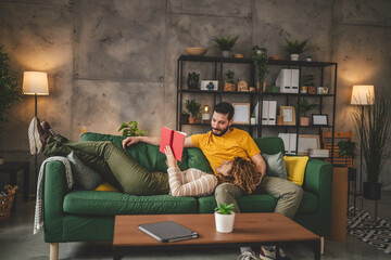 man and woman caucasian adult couple read book at home on sofa bed