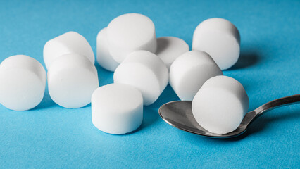 White salt tablets for softening water in a softener on a blue background. The disc held on a spoon