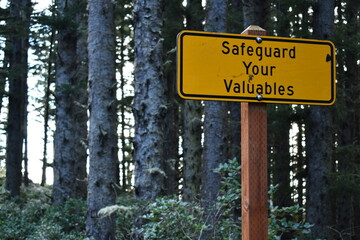 Safeguard your valuables sign, bright yellow and in the forest.
