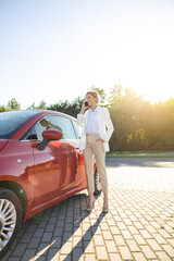 Successful woman making conversation calling via cellphone near her automobile