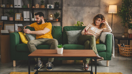 man and woman read book and use digital tablet at home on sofa bed