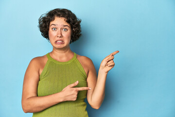 Young Caucasian woman with short hair shocked pointing with index fingers to a copy space.