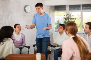 Friendly interested young student taking part in group discussion of study topics with coursemates ..