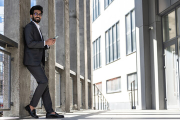 Stylish young businessman in office area with a phone in hands