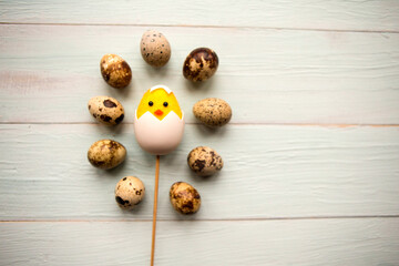 Toy chicken and quail eggs on wooden background, top view. Easter concept. Copy space for the text