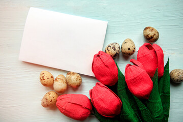 Red craft tulips, quail eggs and white mockup blank on wooden background, top view. Easter concept