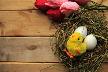 Flat lay photo with chicken eggs and toy chicken in straw nest and bouquet of tulips. Easter...