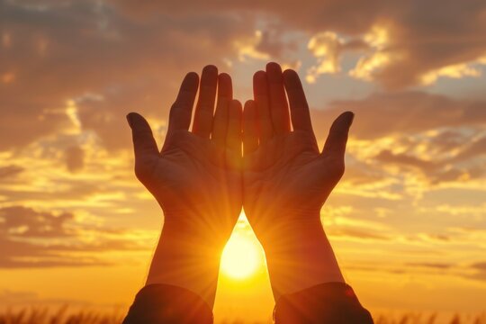 Hands raised in worship to the sunset sky.
