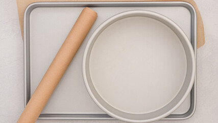 Composition showcasing parchment paper and an array of baking pans, capturing the essential tools...