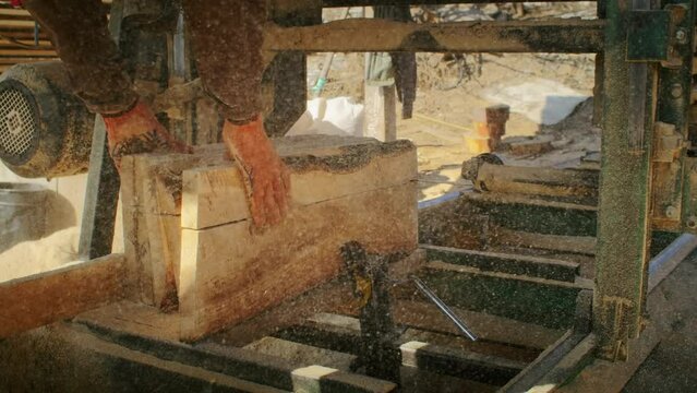 Worker operating a sawmill cutting logs. Industrial woodworking and timber processing concept. Manual labor and machinery at work scene for manufacturing and carpentry themes.