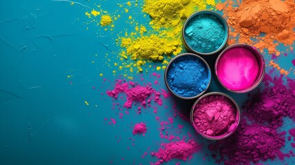 Vibrant Holi powder in pink, yellow, blue, and orange hues scattered on a turquoise surface