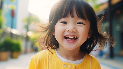 Happy Little Asian Girl child shows front teeth with a big smile and laughs: funny smiley face, healthy smiley face, cute smiley face, cute kid.Joyful girl of an Asian primary school student - obrazy, fototapety, plakaty