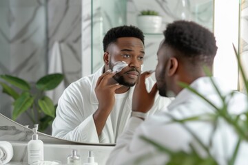 A man applying facial moisturizer in front of a bathroom mirror.