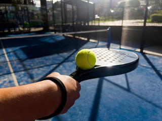 Pala de pádel con una pelota para jugar el deporte de mayor crecimiento en los últimos años a nivel mundial. Cancha de pádel en verano, el momento perfecto para practicar esta disciplina deportiva.