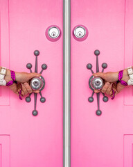 Pink door with a woman's hands holding doorknobs