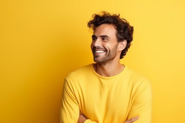 Portrait of handsome young man in yellow sweater smiling over yellow background