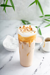 Caramel milk tea latte in a tall glass with cold foam and caramel sauce