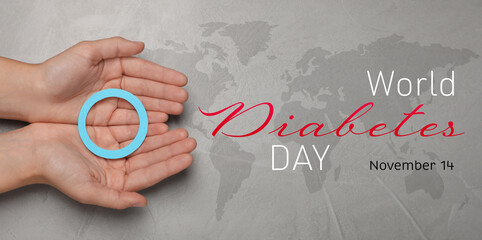 World Diabetes Day. Woman holding blue paper circle at grey table with world map, top view. Banner...