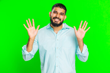 Young Indian man smiling friendly at camera, waving hands gesturing hello greeting or goodbye welcoming with invitation hospitable expression. Arabian guy isolated on green chroma key background