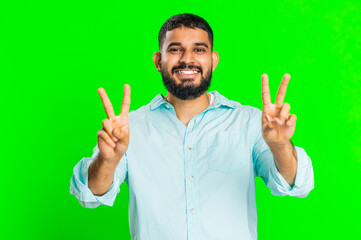 Happy Indian young man showing victory sign, hoping for success and win, doing peace gesture,...