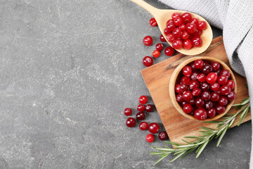 Fresh ripe cranberries and rosemary on grey table, flat lay. Space for text