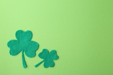 St. Patrick's day. Decorative clover leaves on green background, flat lay. Space for text