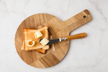 Tasty butter curls, knife and toasts on white marble table, top view