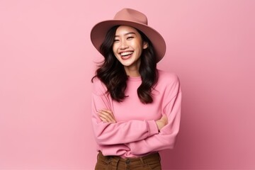 Portrait of a smiling young asian woman with hat on pink background
