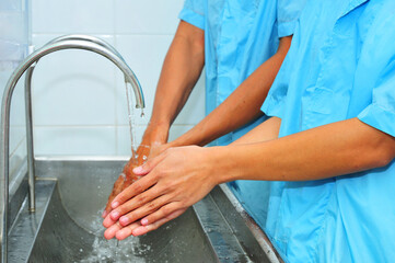 Male and female washing hands in factory(sanitation)